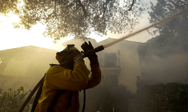 A firefighter from Kern County, Calif., works to put out hot spots during a wildfire Saturday, Dec....