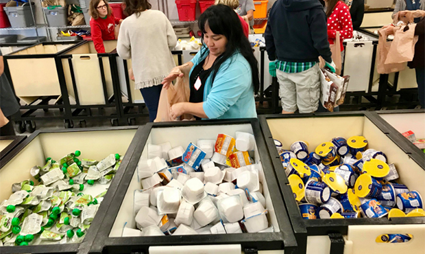 A volunteer with Arizona Brainfood fills a bag of food for Valley schoolchildren to take home over ...