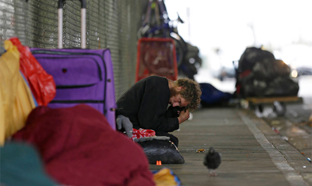 In this Oct. 12, 2017 photo, Dominic, who battles mental illness, sits on a sidewalk under the Smit...
