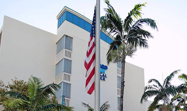 A security guard lowers the U.S. flag to half staff at the Broward Health Medical Center on Thursda...