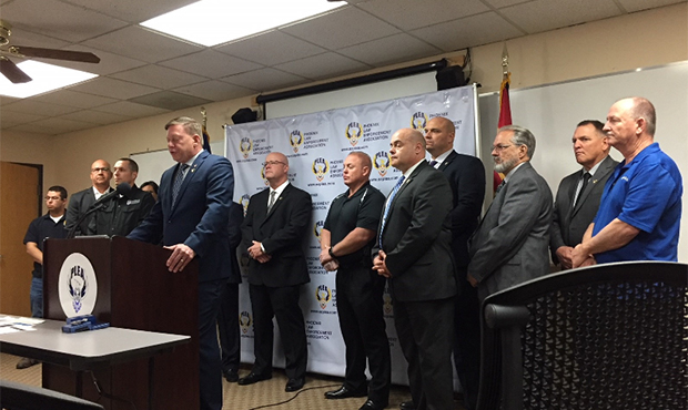 PLEA President Ken Crane at podium; PLEA board behind him. (KTAR News/Kathy Cline)...