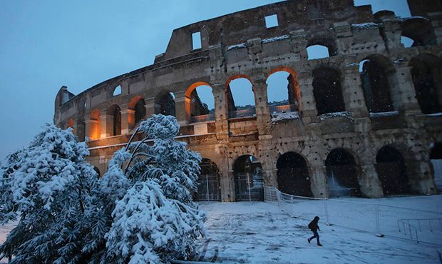 People walk along the ancient Colosseum blanketed by the snow in Rome, Monday, Feb. 26, 2018. (AP P...