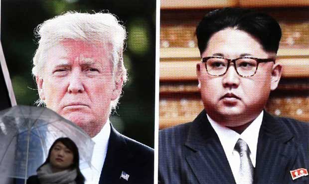 A woman walks by a huge screen showing U.S. President Donald Trump, left, and North Korea's leader ...