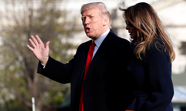 President Donald Trump, accompanied by first lady Melania Trump, waves as he walks on the South Law...