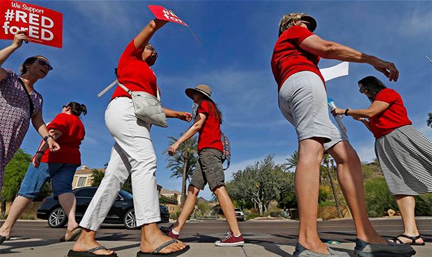 Arizona teachers protest their low pay and school funding in front of a local radio station waiting...
