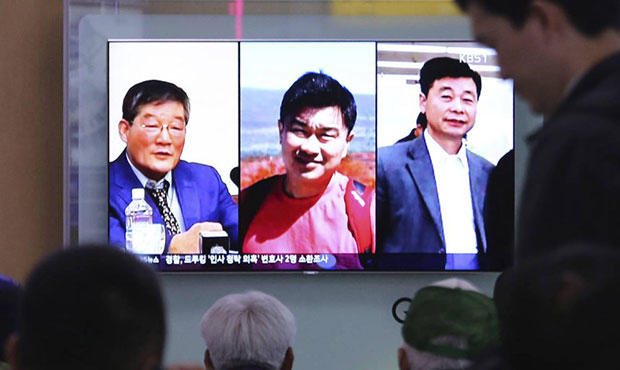 People watch a TV news report on screen, showing portraits of three Americans, Kim Dong Chul, left,...