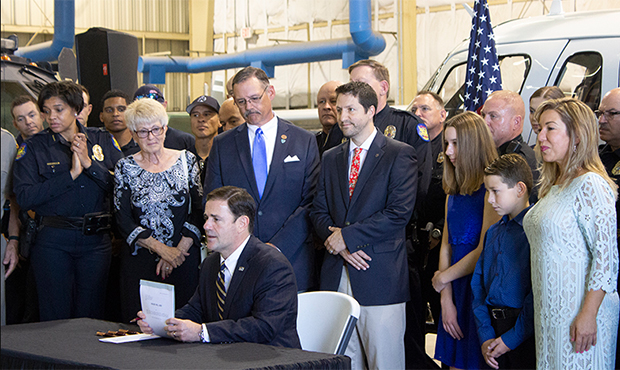 Gov. Ducey poses at the ceremonial signing of the “Officer Craig Tiger Act” alongside the polic...