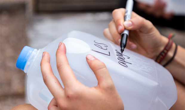 Vanessa Savel writes in Spanish “We support you” on a water jug left for migrants. Other messag...
