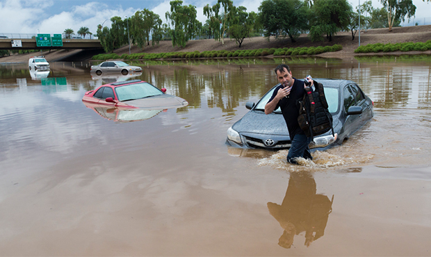 Jim Sampson retrieves items from his 2002 Toyota Corolla stuck in flood waters on I-10 east at 43rd...