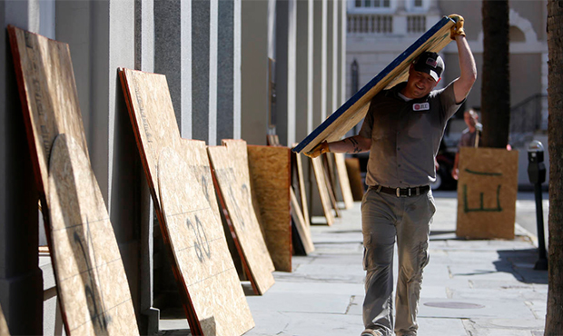 Preston Guiher carries a sheet of plywood as he prepares to board up a Wells Fargo bank in preparat...