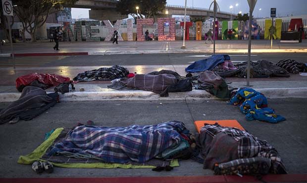 Migrants sleep on a street near the Chaparral border crossing in Tijuana, Mexico, Friday, Nov. 23, ...