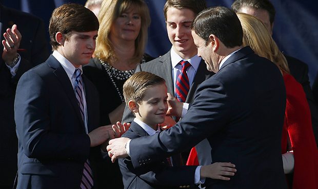 Shortly after being sworn in, Arizona Gov. Doug Ducey, right, gets a hug from son Sam Ducey, middle...