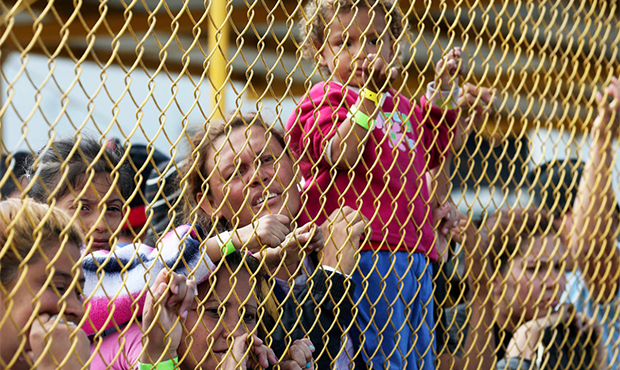 Central American immigrant families look out through the fence of a shelter in Piedras Negras, Mexi...