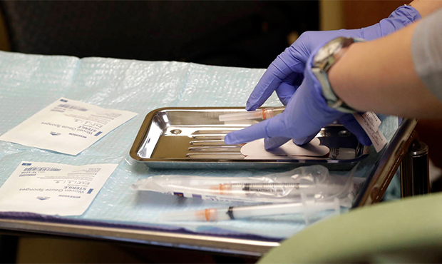 File - In this Feb. 13, 2019, file photo, a health care worker prepares syringes, including a vacci...