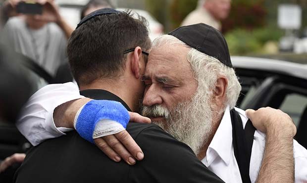Rabbi Yisroel Goldstein, right, is hugged as he leaves a news conference at the Chabad of Poway syn...