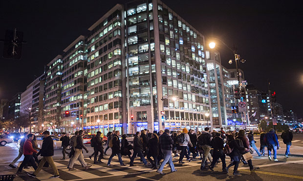Commuters walk past an office building on the way to a metro station at the end of the work day. (A...