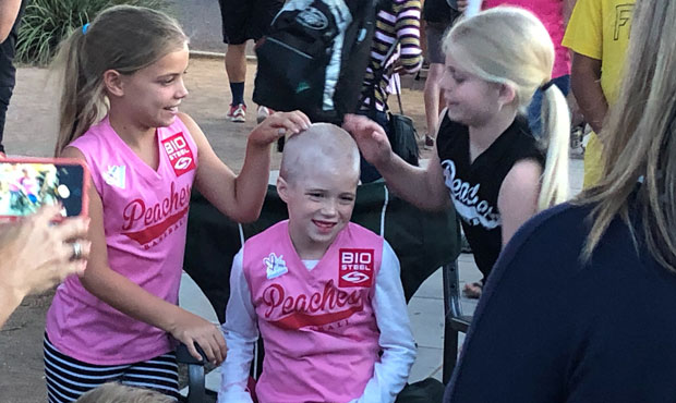 With the support of teammates, Leighton Accardo shows her newly shaved head. She is undergoing trea...