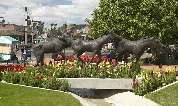 A sculpture of running horses and beautiful spring flowers in Old Town of Scottsdale, Arizona (Phot...