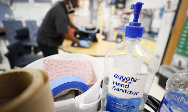 A bottle of hand sanitizer sits on a cart as Des Moines Public Schools custodian Tracy Harris clean...