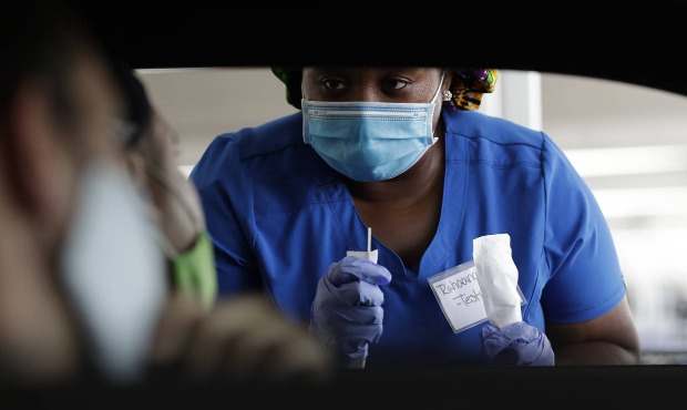 Healthcare worker instructs passengers how to use a nasal swab, Friday, July 24, 2020, at a drive-t...