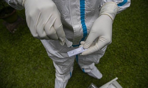 A health worker tests a nasal swab sample for COVID-19. (AP Photo/Anupam Nath)...