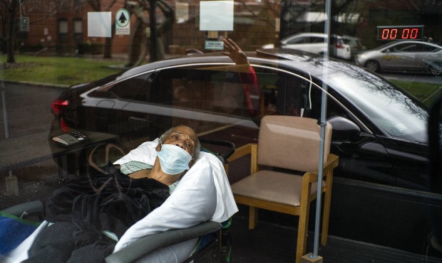 Family members, reflected in the window, wave goodbye to nursing home resident Barbara Farrior, 85,...