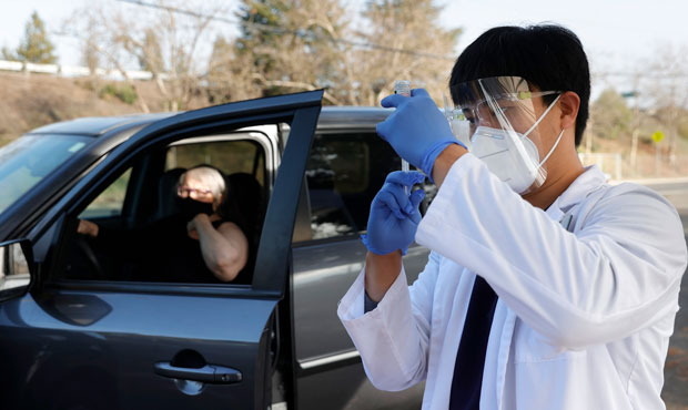 Safeway pharmacist Preston Young fills a syringe with Moderna COVID-19 vaccination during a drive-t...