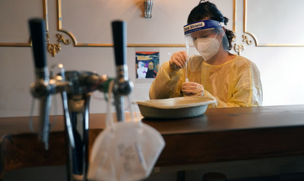 Doctor Jule Teufel stands at the bar to place a throat and nose swab sample into a plastic vial of ...