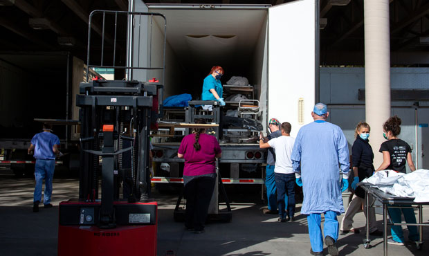 Employees of the Pima County Medical Examiner's office move bodies into a refrigerated semi-truck a...