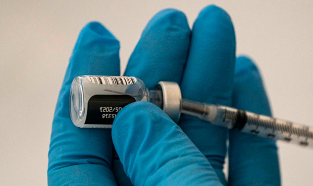 A pharmacist prepares COVID-19 vaccines for patients arriving at Town Toyota Center on January 26, ...
