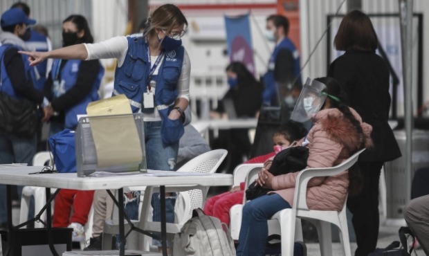 A member of the International Organization for Migration gives instructions to a migrant family bef...