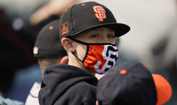 A young baseball fan wears a face mask while watching a spring baseball game between the San Franci...