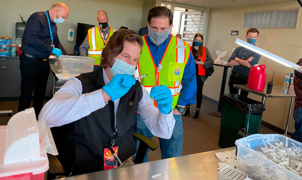 Arizona Gov. Doug Ducey looks on while shots are prepared at the Phoenix Municipal Stadium COVID-19...