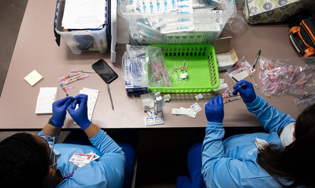 Nurses fill syringes with doses of the Johnson & Johnson COVID-19 vaccine at Wayside Christian Miss...
