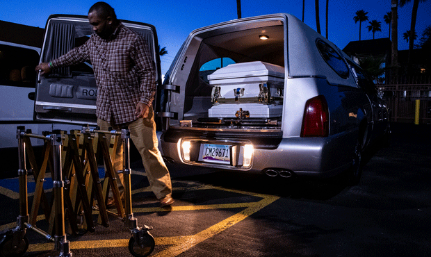 Office manager Reginald Burgan places a casket in a hearse at the end of a shift outside Peace Chap...