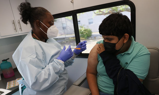 Jean Fletes, 13, receives a Pfizer-BioNTech COVID-19 vaccine from Delores Fye, a licensed practical...