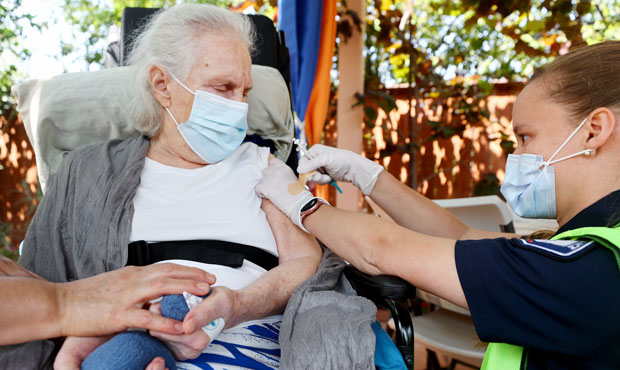 Barbara Pople prepares to apply an adhesive bandage after administering a COVID-19 vaccination dose...