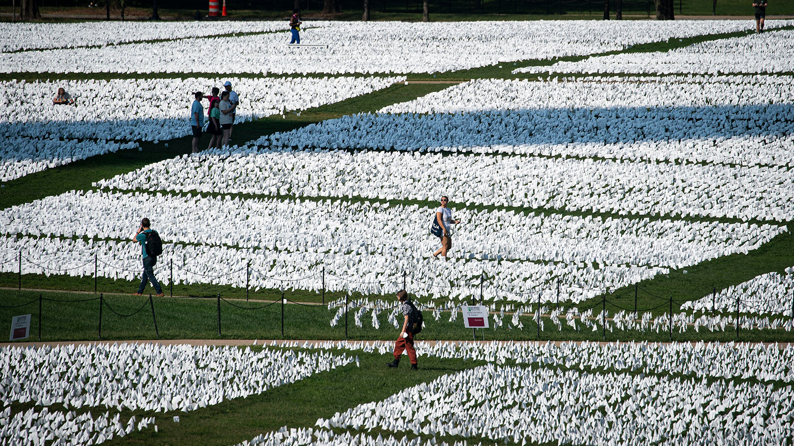 People walk through the flags of the "In America: Remember" public art installation near the Washin...