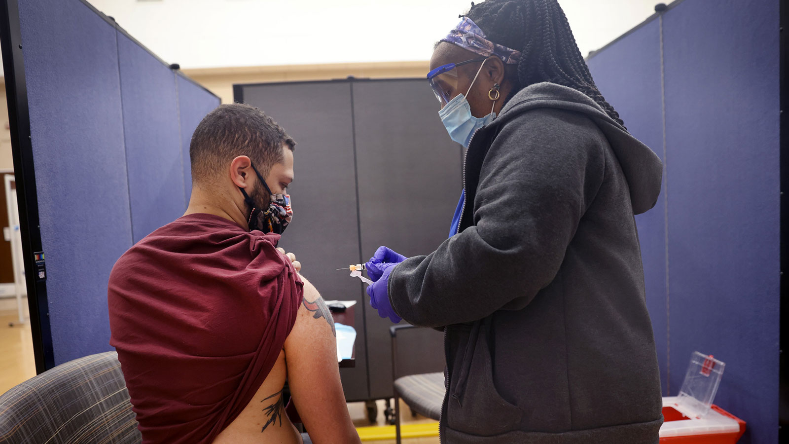 Lisa McCray administers a COVID-19 vaccine and influenza vaccine to Marine Corps veteran Brandon Bu...