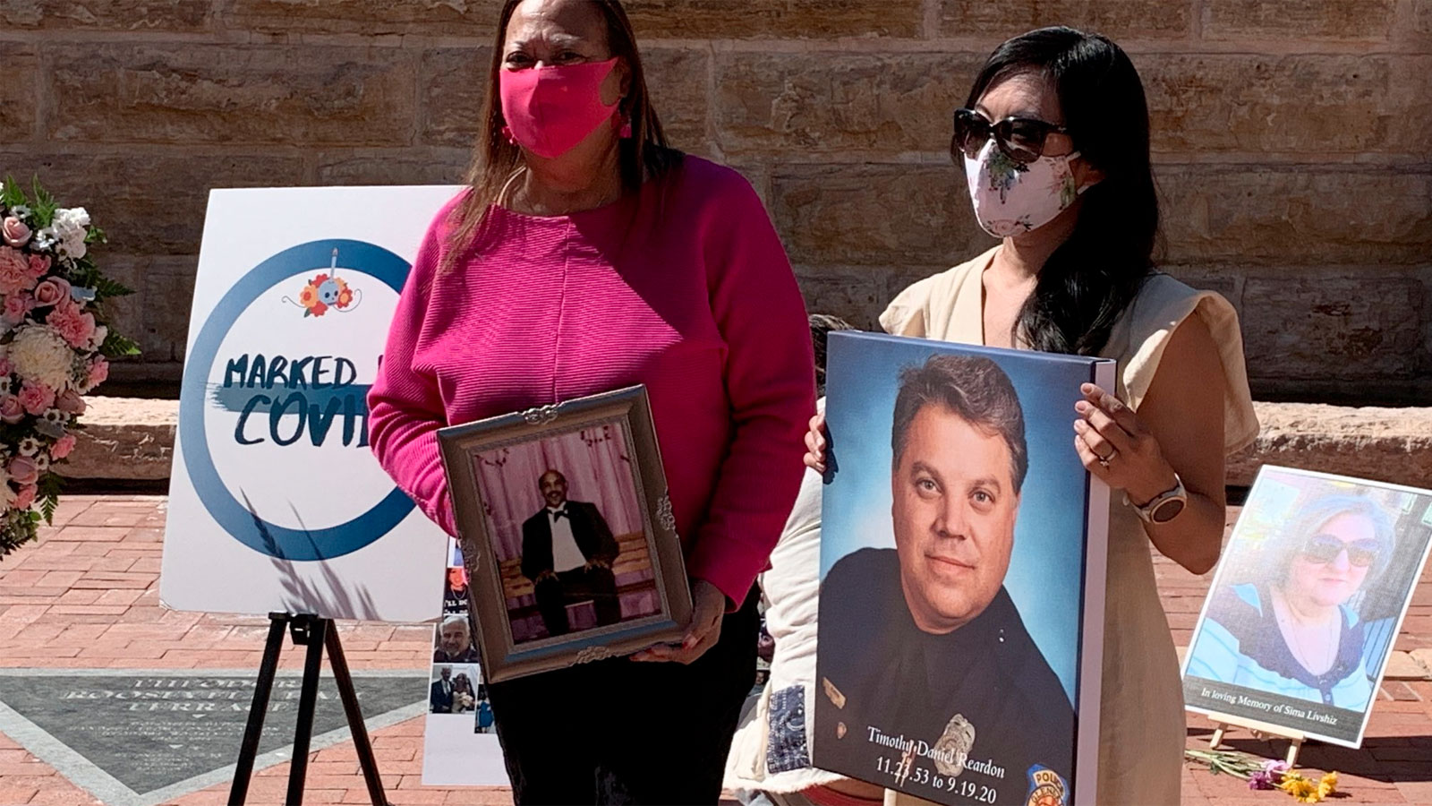 Arizona residents hold photos of loved ones lost to COVID-19 during a memorial event in Tempe, Ariz...