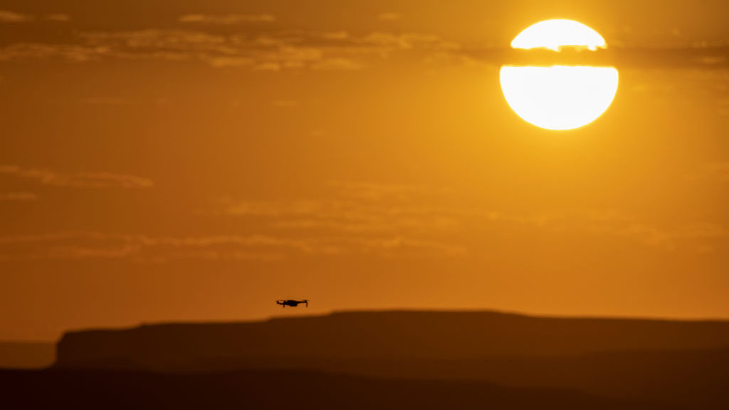 A man flies a drone as the sun rises over Lake Powell at Alstom Point on September 3, 2022 near Pag...