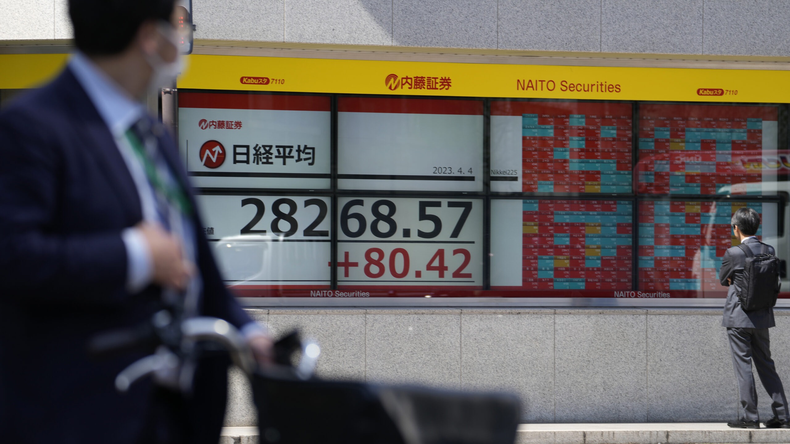 People look at an electronic stock board showing Japan's Nikkei 225 index at a securities firm Tues...