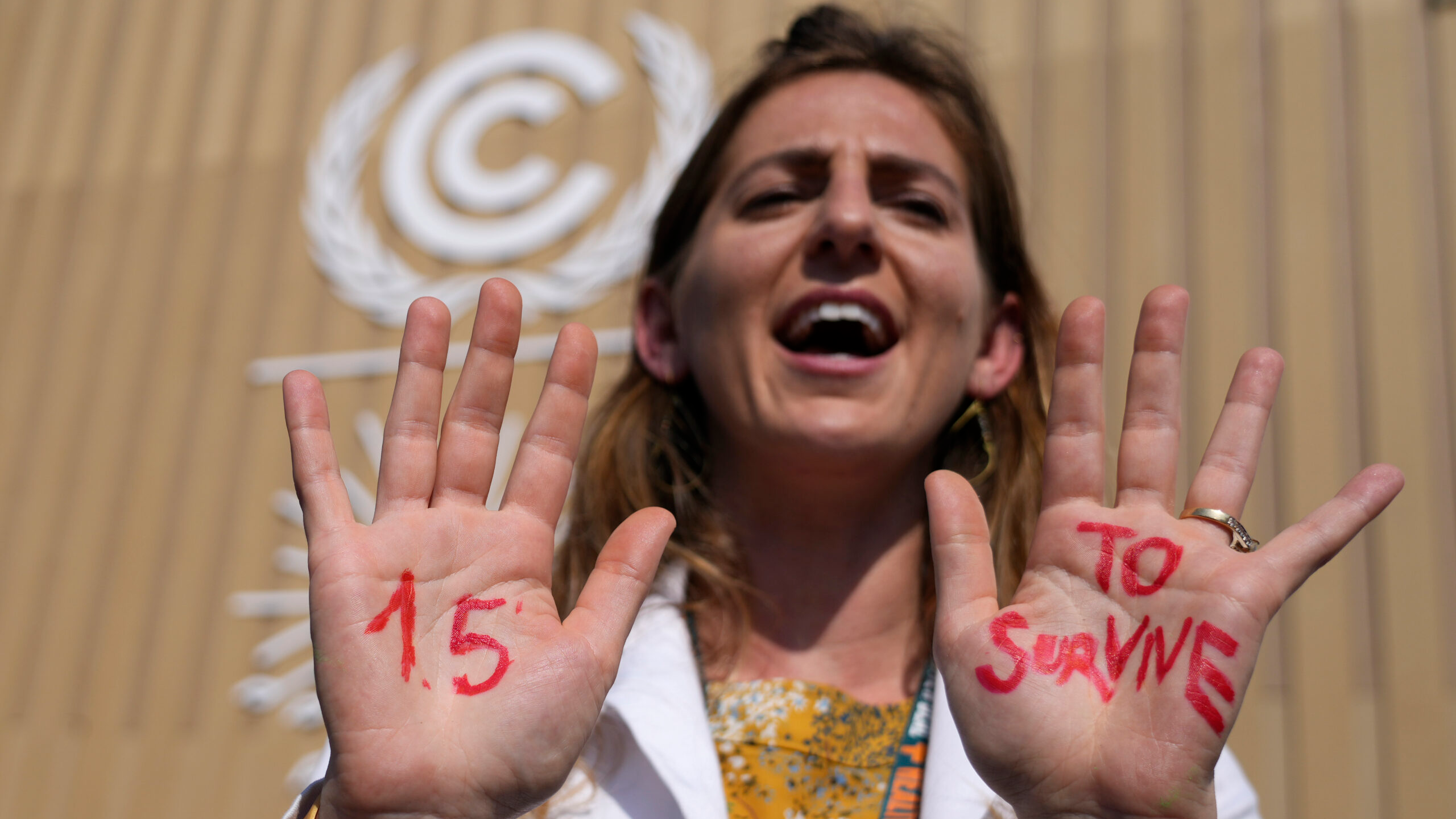 A demonstrator shows her hands reading "1.5 to survive" at a protest advocating for the warming goa...