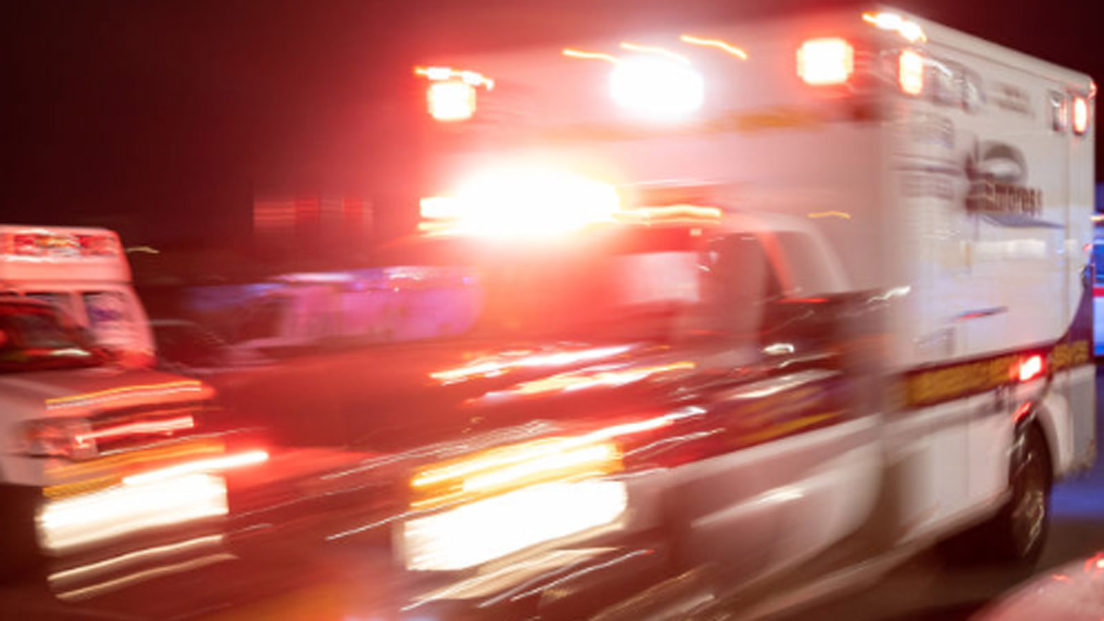 Blurry image of an emergency vehicle or ambulance with lights on at night...