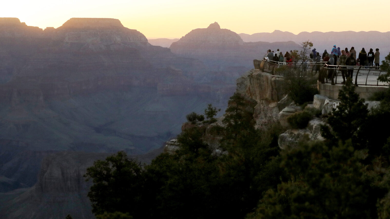 People gather around rim of Grand Canyon at sunrise...