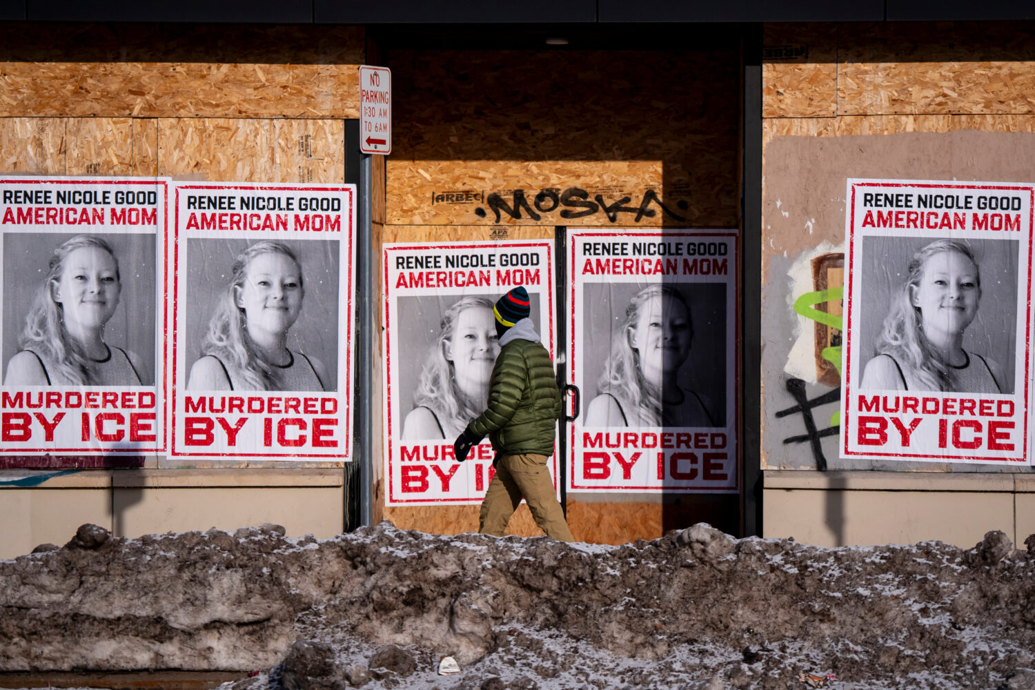 A person walks past signage for Renee Good, who was fatally shot by an ICE officer earlier in the w...