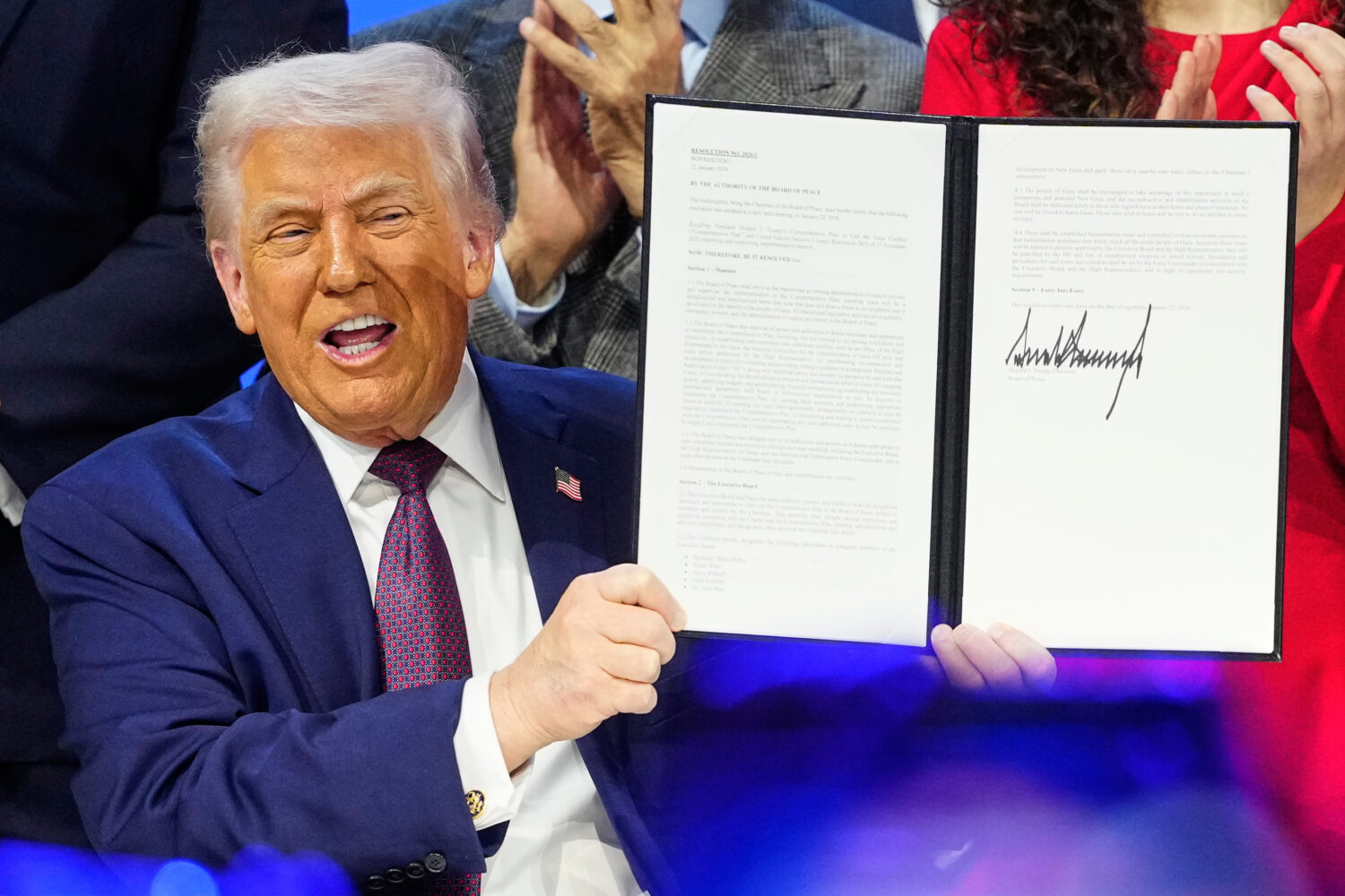 President Donald Trump holds the charter during a signing ceremony on his Board of Peace initiative...