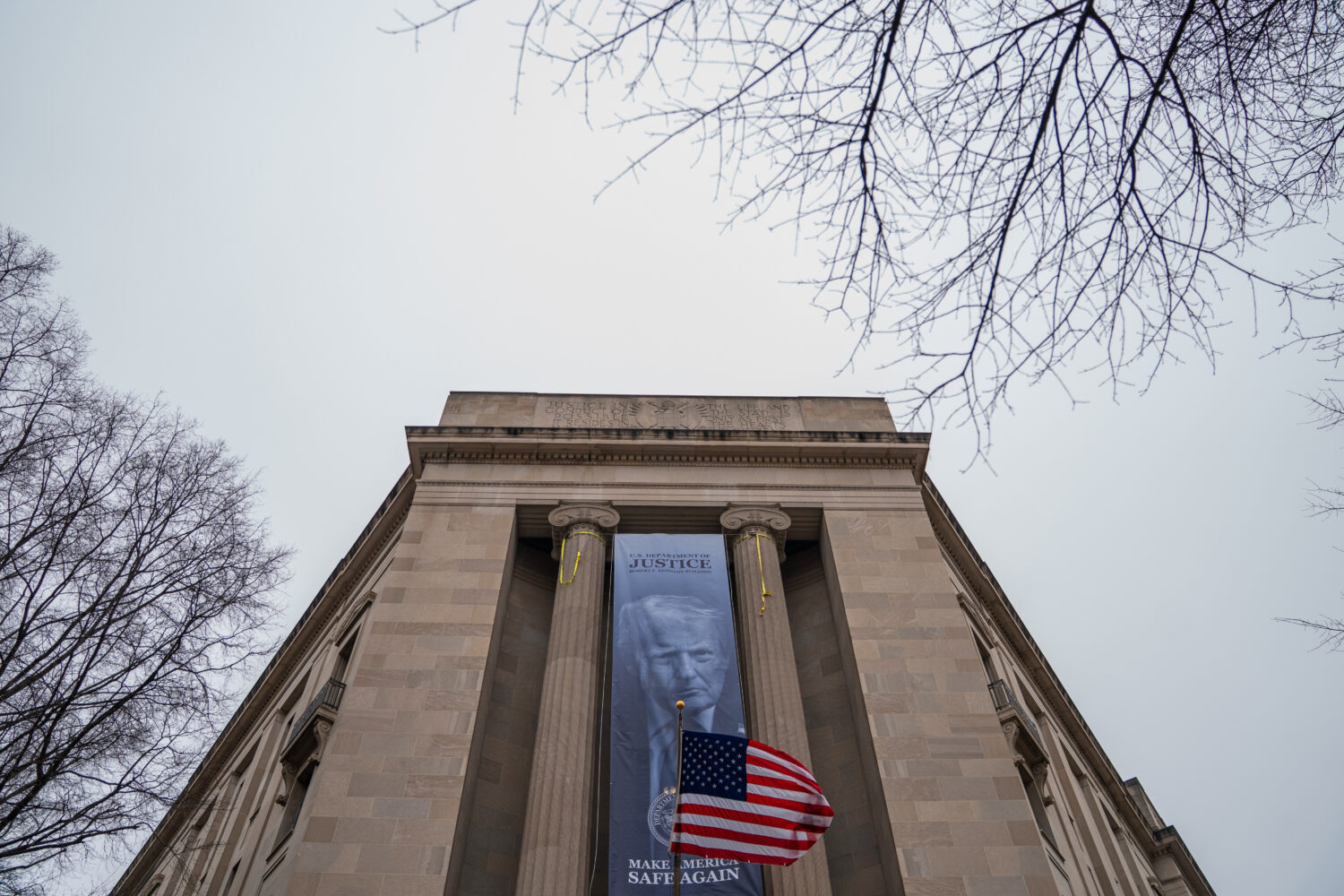 A banner showing President Donald Trump is hung from the Department of Justice, Thursday, Feb. 19, ...