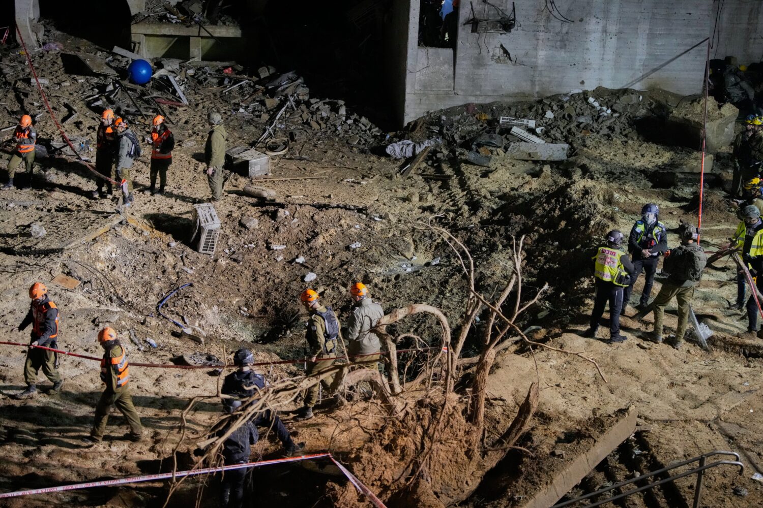 Israeli security forces and rescue teams inspect the crater left by an Iranian missile in Arad, sou...