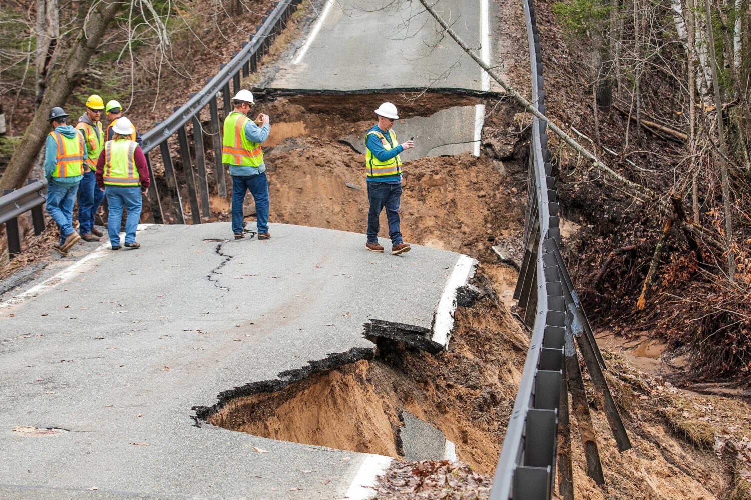 A team from the Michigan Department of Transportation inspects a washed-out bridge on M-119 between...